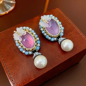 Dettaglio di orecchini vintage con farfalla in resina, cristalli e perle pendenti