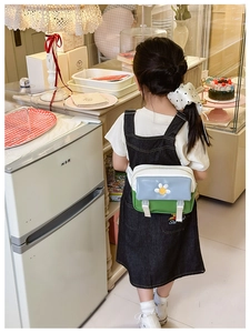 Detail of color-block kids crossbody bag featuring white daisy embroidery and dual buckles