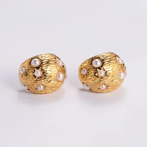 Detailed shot of gold-plated earrings with hammered texture, pearls, and star accents