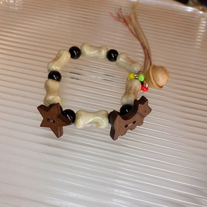 Macro view of handmade ceramic bead bracelet with star and puppy wooden pendants