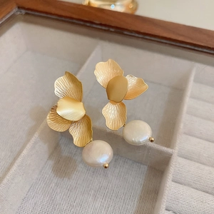Détails de boucles d'oreilles fleurs dorées avec perles blanches dans un coffret luxe