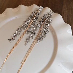 Détail de boucles d'oreilles franges épi de blé en métal sur une assiette blanche