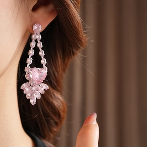 Gros plan détaillé d'une boucle d'oreille cœur en zircon rose sur l'oreille d'un mannequin