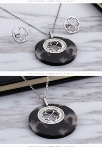 Dettaglio degli orecchini a quadrifoglio argento e set collana con ciondolo tartaruga grigia