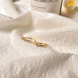 Detailed close-up of slim gold knot rings on white fabric for elegant stacking style