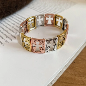 Detail of tricolor cross cutout stretch bracelet with textured finish on book