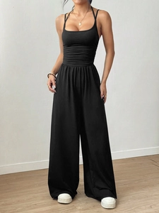 Detail view of women's black sleeveless top and high-waisted wide-leg trousers outfit