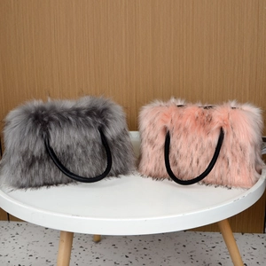 Faux fur tote bags in grey and pink with black handles on a white round table