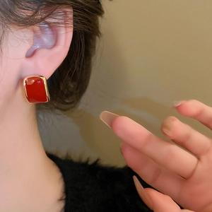 Close-up of vintage rectangular red enamel stud earrings with polished gold-tone metal borders