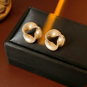 Detail of twisted gold earrings with crystals on a black leather jewelry box