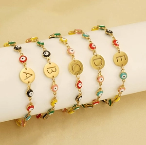 Detail of gold evil eye bracelets with personalized letter charms A to E on white display
