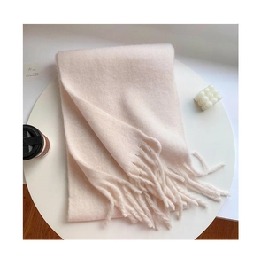 Detailed close-up of thick pastel pink scarf with long tassels on a white tray
