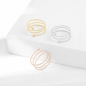 Dettaglio di anelli a spirale aperti in oro, argento e oro rosa con sfere in metallo