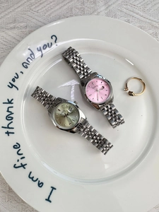 Detail of steel strap women watches with date display on a decorative ceramic plate