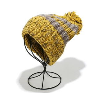 Detail of winter knit beanie showing yellow pompom and thick ribbed texture on display