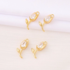 Macro shot of gold tulip jewelry pendants with teardrop cubic zirconia on fabric