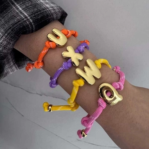 Detailansicht bunter Seilarmbänder mit vergoldeten 18K Bubble-Initialen-Anhängern