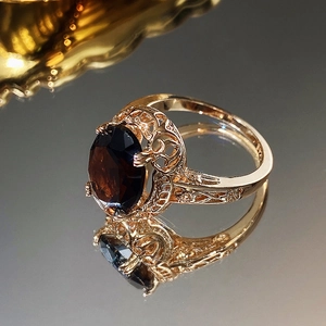 Macro shot of vintage rose gold ring with large oval red zircon and luxury engraving