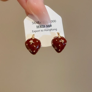 Dettaglio degli orecchini a fragola con smalto rosso e piccoli accenti di stelle dorate