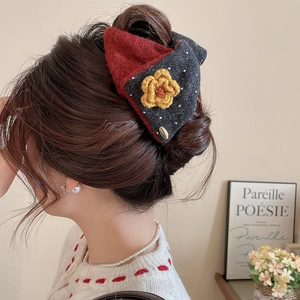Close-up of red and grey knitted bow hair claw clip with a yellow flower on hair