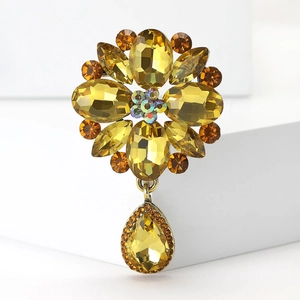 Close-up of golden floral brooch with yellow crystals and teardrop pendant details