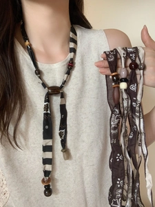 Detail of vintage bohemian fabric necklaces featuring striped patterns and wooden beads