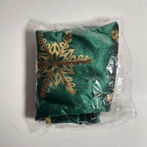 Detail of green velvet Christmas tree skirt with golden sequin snowflake in packaging