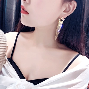 Detailed close-up of a long star-shaped tassel earring with sparkling rhinestones on model
