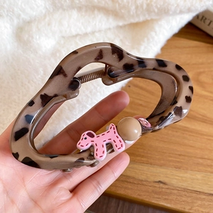 Close-up of leopard print acrylic claw clip with pink cartoon dog and small rhinestone