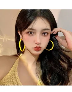 Close-up of vibrant yellow acrylic hoop earrings worn by a model for a stylish look