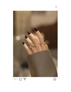 Detail of gold butterfly ring and pink gemstone ring on hand with black nail polish