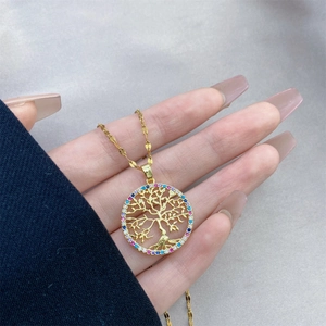 Gold tree of life necklace with colorful zircon stones held against a gray background