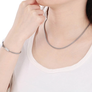 Detail von silbernen geflochtenen Halsketten und Armbändern am Modell vor weißem Hintergrund