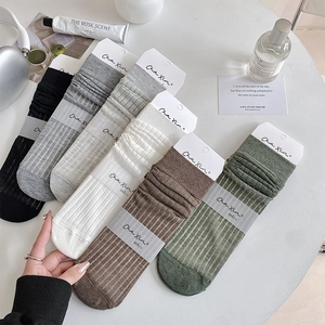 Flat lay of colorful ribbed mid-calf socks with ruffle cuffs on a stylish white desk