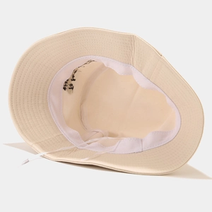 Close-up of the beige cotton bucket hat interior with windproof rope and black embroidery
