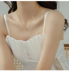 Close-up of minimalist gold beaded necklace with a green Aventurine gemstone pendant on neck