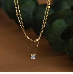 Detail of double-layer necklace with 18K gold beads and four-prong cubic zirconia pendant