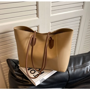 Detail of khaki PU leather tote bag with sturdy shoulder straps on a sleek sofa