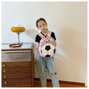 Girl wearing pink soccer print backpack in a cozy indoor setting with lifestyle vibes