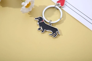 Dachshund enamel keychain with silver ring and red heart pendant on yellow background