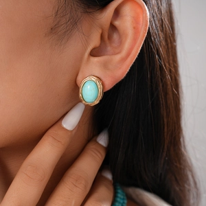 Detailed view of turquoise stone stud earrings with vintage gold textured metal frames