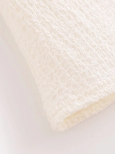 Macro shot of white seersucker fabric showing detailed puckered texture and weave pattern