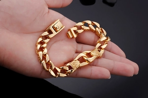 Detail of vintage gold chunky Cuban link bracelet with engraved decorative clasp closure