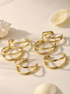 Vue détaillée de boucles d'oreilles créoles torsadées dorées avec décor de coquillage