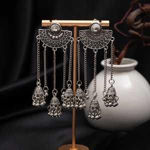 Bohemian vintage long tassel earrings with silver floral carving on a display stand