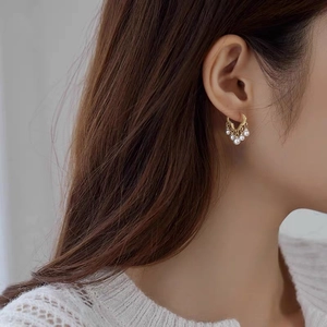 Close-up of elegant gold tassel earrings with pearls on a model for a chic style