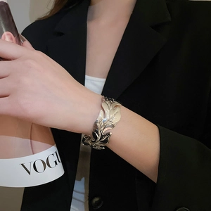 Detailed view of silver leaf-shaped open cuff bracelet with polished metallic texture