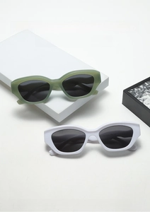 Detail shot of trendy polygon sunglasses in morandi green and white on minimalist props