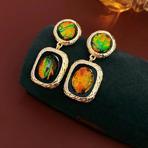 Détail de boucles d'oreilles géométriques dorées vintage avec incrustation en résine