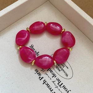 Macro detail of irregular pink acrylic beads with gold metal spacers on a display tray